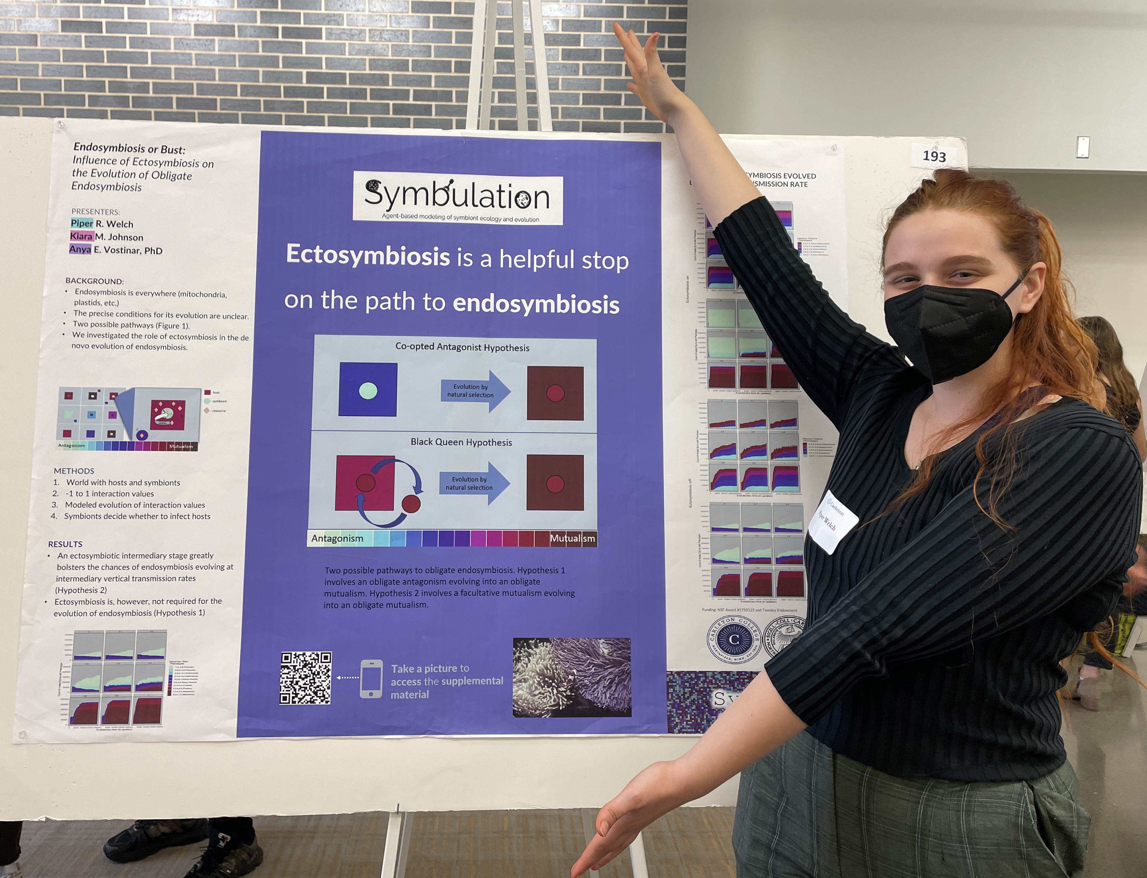 A picture of a research poster with a student standing by it.